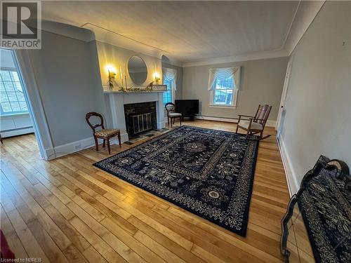 Living room featuring hardwood / wood-style floors, baseboard heating, and crown molding - 166 North Street, Fort Erie, ON - Indoor Photo Showing Living Room With Fireplace