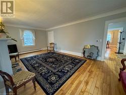 Living area featuring hardwood / wood-style flooring, crown molding, and a baseboard heating unit - 