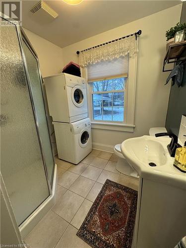 Bathroom with vanity, tile patterned flooring, toilet, walk in shower, and stacked washer / drying machine - 166 North Street, Fort Erie, ON - Indoor Photo Showing Laundry Room