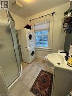 Bathroom with vanity, tile patterned flooring, toilet, walk in shower, and stacked washer / drying machine - 