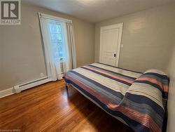 Bedroom with hardwood / wood-style flooring and a baseboard heating unit - 