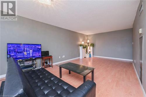 Living room featuring a textured ceiling and hardwood / wood-style flooring - 305 Webb Drive Unit# 308, Mississauga, ON 