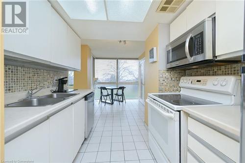 Kitchen featuring white cabinets, stainless steel appliances, and tasteful backsplash - 305 Webb Drive Unit# 308, Mississauga, ON 