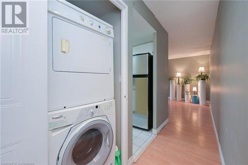 Clothes washing area with light wood-type flooring and stacked washer and dryer - 305 Webb Drive Unit# 308, Mississauga, ON 