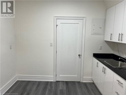 Kitchen featuring white cabinets, dark hardwood / wood-style flooring, electric panel, and sink - 660 Main Street E Unit# 2, Hamilton, ON - Indoor