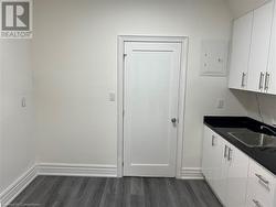 Kitchen featuring white cabinets, dark hardwood / wood-style flooring, electric panel, and sink - 