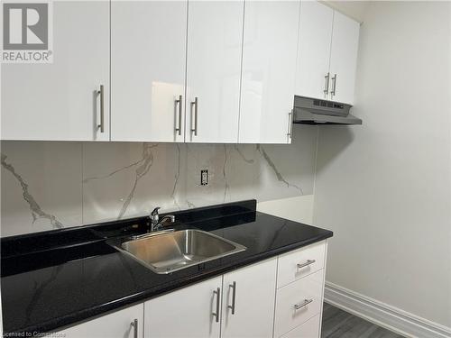 Kitchen featuring backsplash, white cabinetry, sink, and dark wood-type flooring - 660 Main Street E Unit# 2, Hamilton, ON - Indoor Photo Showing Kitchen