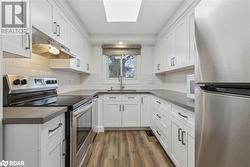 Kitchen featuring white cabinets, sink, appliances with stainless steel finishes, and dark wood-type flooring - 