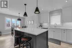 Kitchen with white cabinets, pendant lighting, tasteful backsplash, and sink - 