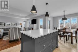 Kitchen with light wood-type flooring, gray cabinets, a kitchen island, and hanging light fixtures - 