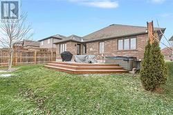 Back of property featuring a yard, a deck, and a hot tub - 