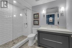 Bathroom featuring a tile shower, vanity, toilet, and tile patterned floors - 