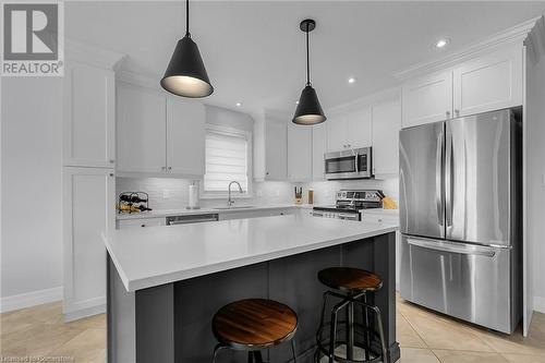 Kitchen featuring white cabinets, a kitchen island, sink, and appliances with stainless steel finishes - 46 Halliday Drive Drive, Tavistock, ON - Indoor Photo Showing Kitchen With Upgraded Kitchen