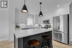 Kitchen featuring white cabinets, a kitchen island, sink, and appliances with stainless steel finishes - 