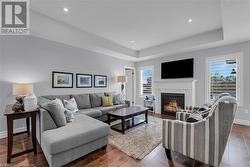 Living room featuring a tray ceiling, a wealth of natural light, and dark hardwood / wood-style floors - 