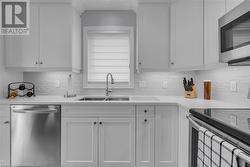 Kitchen featuring white cabinets, sink, appliances with stainless steel finishes, and tasteful backsplash - 