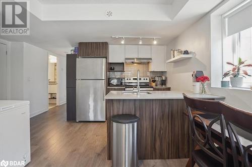 Kitchen featuring sink, white cabinetry, appliances with stainless steel finishes, light hardwood / wood-style floors, and dark brown cabinetry - 1141 Cooke Boulevard Unit# 416, Burlington, ON - Indoor Photo Showing Kitchen