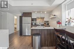 Kitchen featuring sink, white cabinetry, appliances with stainless steel finishes, light hardwood / wood-style floors, and dark brown cabinetry - 