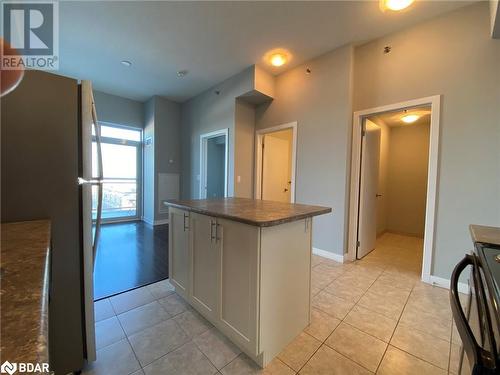 Kitchen featuring light tile patterned flooring, range, white cabinetry, and stainless steel refrigerator - 2486 Old Bronte Road Unit# 813, Oakville, ON 