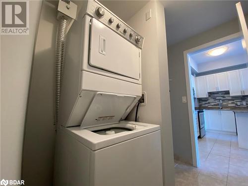 Washroom featuring stacked washer / drying machine, light tile patterned flooring, and sink - 2486 Old Bronte Road Unit# 813, Oakville, ON 