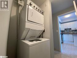 Washroom featuring stacked washer / drying machine, light tile patterned flooring, and sink - 