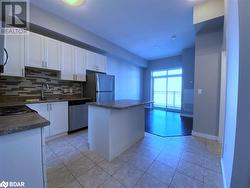 Kitchen with appliances with stainless steel finishes, white cabinetry, a kitchen island, and sink - 