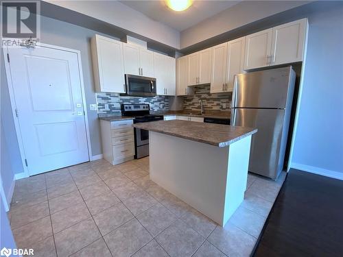 Kitchen featuring backsplash, stainless steel appliances, light tile patterned floors, white cabinets, and a center island - 2486 Old Bronte Road Unit# 813, Oakville, ON 