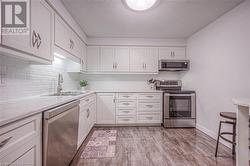 Kitchen featuring white cabinets, sink, a textured ceiling, appliances with stainless steel finishes, and light hardwood / wood-style floors - 