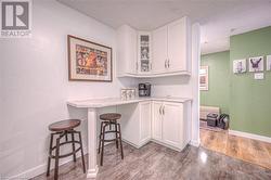 Bar featuring white cabinetry, a textured ceiling, and light wood-type flooring - 