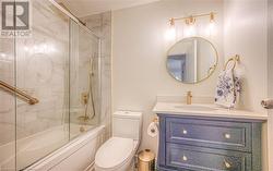 Full bathroom with vanity, toilet, and bath / shower combo with glass door - 