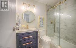 Bathroom with tile patterned floors, vanity, toilet, and a shower with door - 