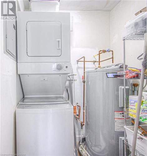 Clothes washing area with water heater and stacked washing maching and dryer - 55 Green Valley Drive Drive Unit# 1806, Kitchener, ON - Indoor Photo Showing Laundry Room