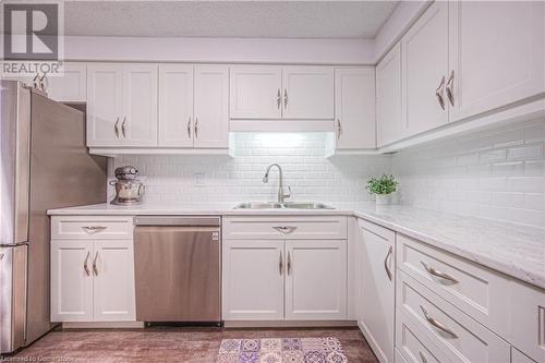 Kitchen with light stone countertops, tasteful backsplash, stainless steel appliances, sink, and white cabinetry - 55 Green Valley Drive Drive Unit# 1806, Kitchener, ON - Indoor Photo Showing Kitchen With Double Sink