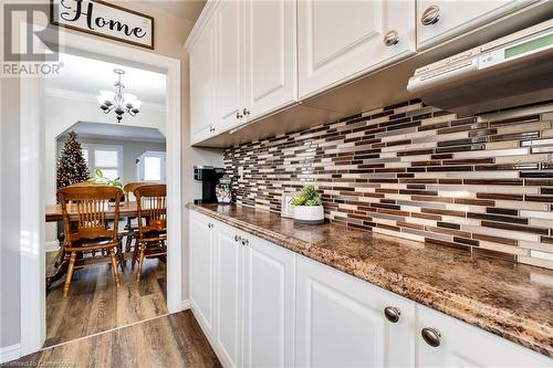 Kitchen with dark stone counters, white cabinets, crown molding, dark hardwood / wood-style floors, and decorative backsplash - 245 St Andrews Street, Cambridge, ON - Indoor