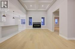 Unfurnished living room featuring beamed ceiling, light wood-type flooring, and coffered ceiling - 