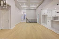 Corridor featuring beamed ceiling, light hardwood / wood-style floors, an inviting chandelier, and coffered ceiling - 