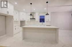 Kitchen with sink, wall chimney exhaust hood, pendant lighting, and a kitchen island - 