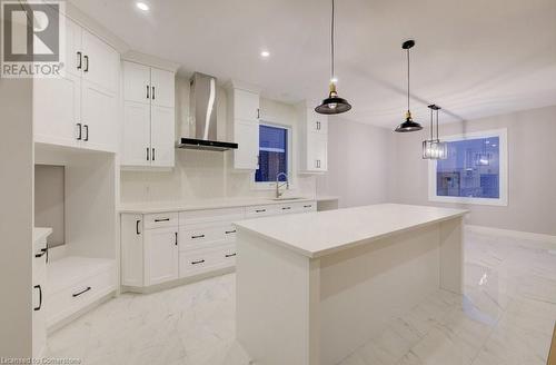 Kitchen with a center island, sink, wall chimney exhaust hood, decorative light fixtures, and white cabinets - 705 Hollinger Drive S, Listowel, ON - Indoor Photo Showing Kitchen