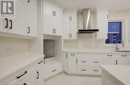 Kitchen with decorative backsplash, white cabinetry, wall chimney exhaust hood, and sink - 705 Hollinger Drive S, Listowel, ON - Indoor