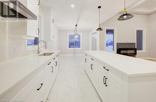 Kitchen with sink, a center island, hanging light fixtures, range hood, and backsplash - 705 Hollinger Drive S, Listowel, ON - Indoor Photo Showing Kitchen With Upgraded Kitchen