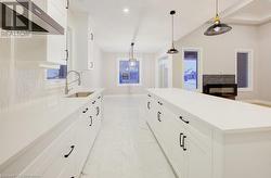 Kitchen with sink, a center island, hanging light fixtures, range hood, and backsplash - 