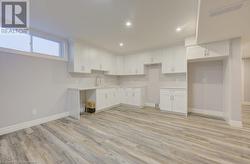 Kitchen with white cabinets, light hardwood / wood-style floors, and sink - 