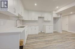 Kitchen featuring white cabinets, light wood-type flooring, and sink - 