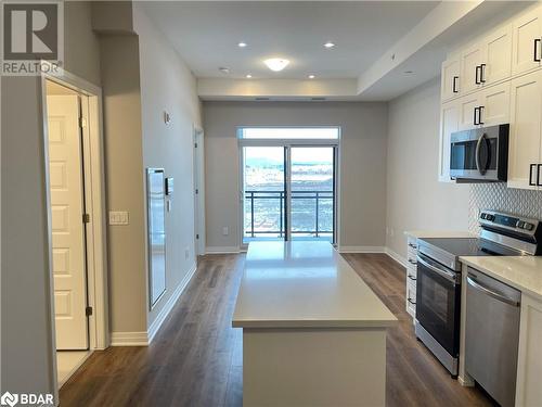 Kitchen featuring decorative backsplash, appliances with stainless steel finishes, dark wood-type flooring, white cabinets, and a kitchen island - 490 Gordon Krantz Avenue Unit# 602, Milton, ON - Indoor Photo Showing Kitchen