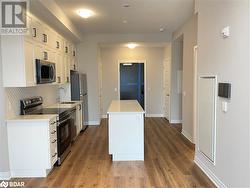 Kitchen featuring appliances with stainless steel finishes, backsplash, sink, hardwood / wood-style floors, and white cabinetry - 