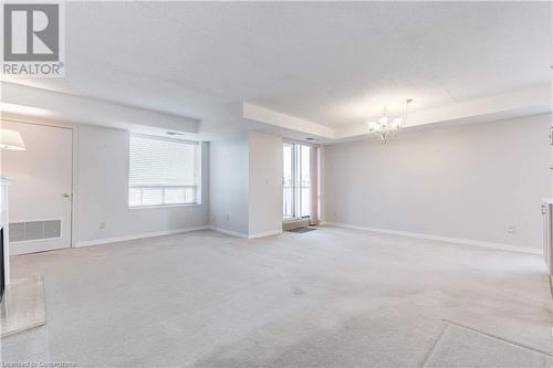 Spare room with a textured ceiling, light carpet, and a chandelier - 870 Upper Wentworth Street Unit# 202, Hamilton, ON - Indoor Photo Showing Other Room