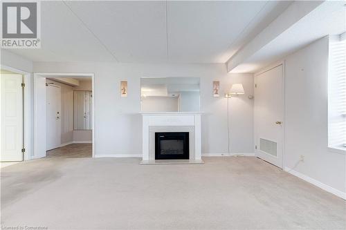 Unfurnished living room with light carpet and a textured ceiling - 870 Upper Wentworth Street Unit# 202, Hamilton, ON - Indoor Photo Showing Living Room With Fireplace