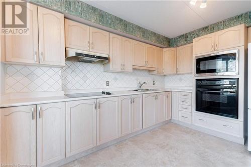 Kitchen featuring stainless steel microwave, black oven, stovetop, and light brown cabinets - 870 Upper Wentworth Street Unit# 202, Hamilton, ON - Indoor Photo Showing Kitchen