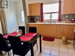 Kitchen featuring decorative backsplash, sink, and light tile patterned flooring - 