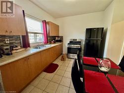 Kitchen featuring stainless steel appliances, sink, tasteful backsplash, and light tile patterned floors - 